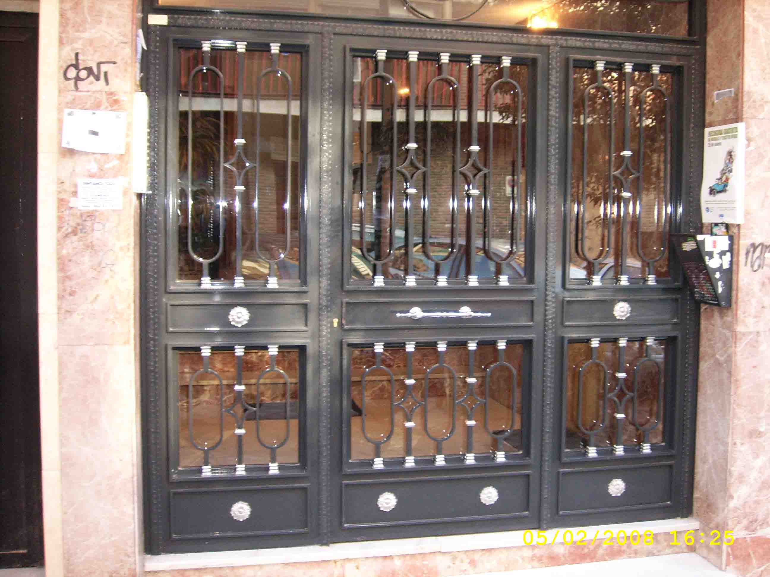 Puerta de Comunidad con elementos decorativos y cristaleras por Cerrajería Keymar